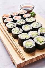  Wooden board with avocado, salmon and cucumber sushi makis on a marble surface