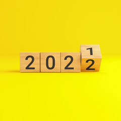 Flip over wooden cube block with new year 2022 on yellow background.