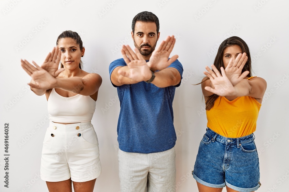 Sticker group of young hispanic people standing over isolated background rejection expression crossing arms 