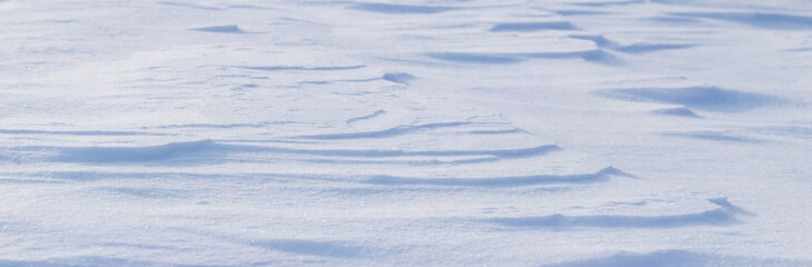 Fototapeta na wymiar Snowy background, snow-covered surface of the earth after a blizzard in the morning in the sunlight with distinct layers of snow