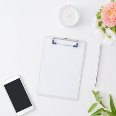 Flat lay mockup clipboard, smartphone, flowers in a vase on a light background