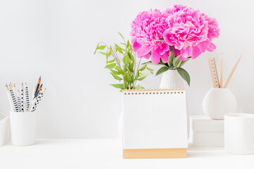 Mockup white desk calendar and pink peonies in a vase on a light background