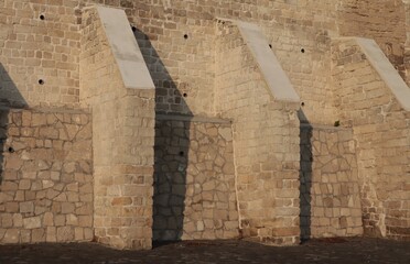 A fragment of the fortified wall of an ancient castle made of stone.