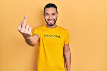 Hispanic man with beard wearing t shirt with happiness word message showing middle finger, impolite...
