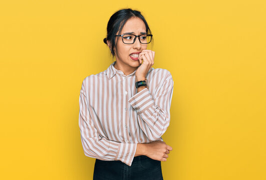 Young hispanic girl wearing casual clothes and glasses looking stressed and nervous with hands on mouth biting nails. anxiety problem.