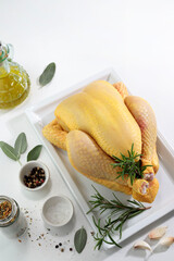 Pollo intero crudo con spezie ed erbe aromatiche isolate su sfondo bianco. Direttamente sopra. - obrazy, fototapety, plakaty