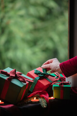 Holiday gift boxes and female hand on a window in house