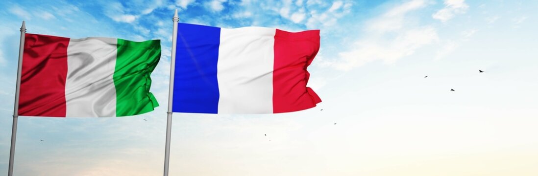 Italy and France Flags are waving in the spring of the blue sky. 