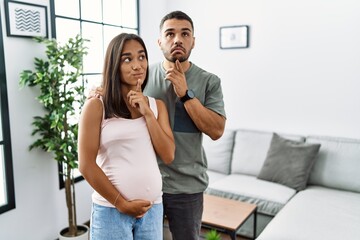 Young interracial couple expecting a baby, touching pregnant belly thinking concentrated about...