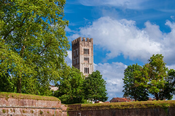 Lucca charming historical center. View of the iconic St Frediano medieval bell tower with ancient city walls - obrazy, fototapety, plakaty