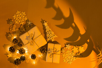 Christmas at sunset. Gifts, a garland with deer, decorations, snowflakes and a tree shadow in warm orange light. Top view