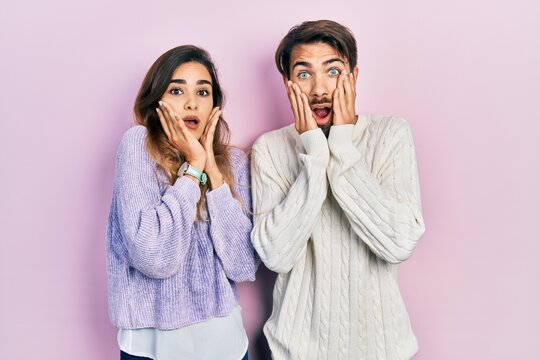 Young hispanic couple wearing casual clothes afraid and shocked, surprise and amazed expression with hands on face