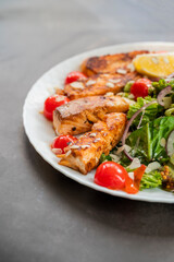 salad dish with slices of baked fried salmon with vegetables and lettuce