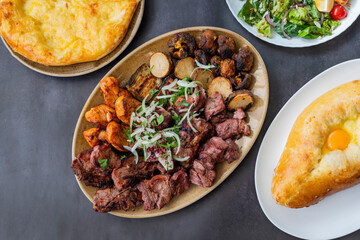 cuts of meat barbecue kebabs grilled pork and beef and chicken on a plate with onions and vegetables and potatoes in a restaurant