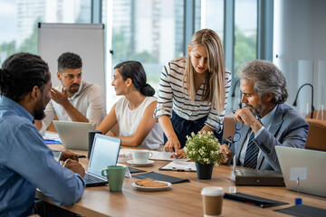 Young designer giving some new ideas about project to his partners in conference room. Business people discussing over new business project in office. Business People Working in The Office