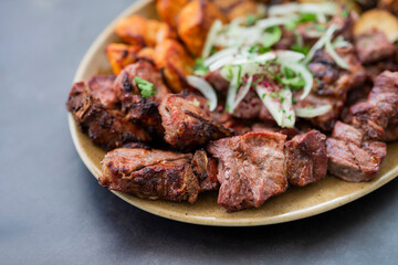 cuts of meat barbecue kebabs grilled pork and beef and chicken on a plate with onions in a restaurant