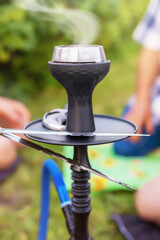 Obraz premium hookah with smoking coals, people are sitting around the hookah and smoking it outdoors