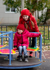 Two cute girls ride a swing. Childhood. Autumn.