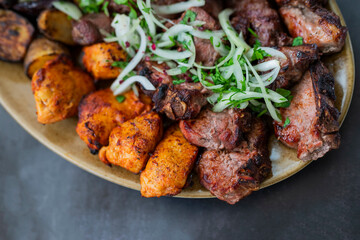 cuts of meat barbecue grilled pork and beef and chicken on a plate with onions in a restaurant