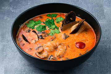 Traditional spicy Thai soup Tom Yum with shrimp and seafood, classic dish of cuisine of Thailand