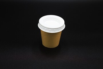 Side view of a coffee to go cup with a black background .