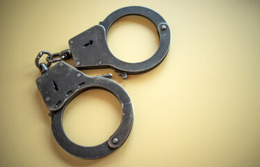 Metal handcuffs of silver color on a yellow isolate. Criminal chronicle.Police bracelets. Arrest of the criminal.