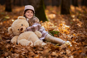Young caucasian girl playing with her plush bear toy outdoor