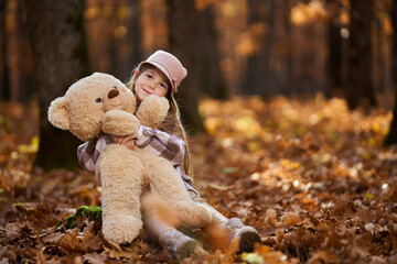 Young caucasian girl playing with her plush bear toy outdoor