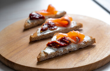 Fresh toast with smoked salmon, sun-dried tomatoes and philadelphia cheese on toasted bread. Clean eating, dieting or recipe of healthy snack sandwich.
