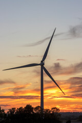 Windturbine silhouetted at sunset generating clean energy