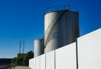 Large shiny steel storage tanks with metal ladders