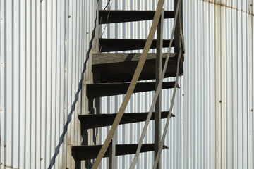 Obraz premium Detail of a shiny steel storage tank with metal ladders and its shadow