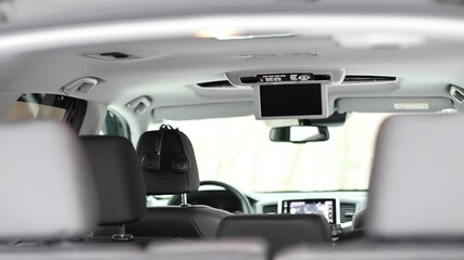Car interior with various entertainment options. Advanced multimedia system, ceiling monitor. Full-interior view of wireless headphones