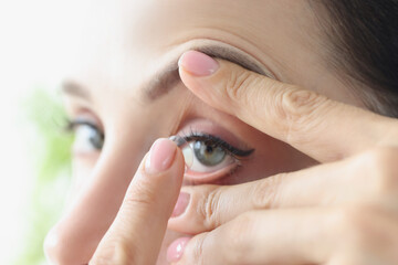 Woman puts on long-term soft contact lenses closeup