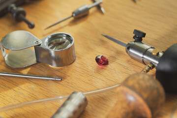 Jeweler's workplace. Tools and equipments for jewelry work on an antique wooden desktop. Jeweller, engraver at work.