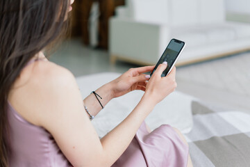 Cropped view of female hands holding smart phone. Woman with cell phone in home. Selective focus