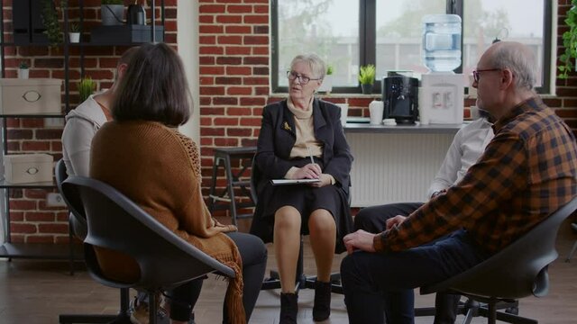 Man with depression making confession at aa therapy meeting with alcoholics people. Person telling addiction story to receive help and advice from therapist at support rehab group.