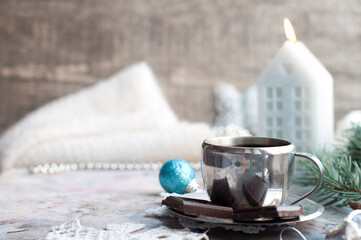 Obraz na płótnie Canvas Silver cup of coffee espresso with chocolate, candle, fir, knitted snowflakes, blue ball, silver decor, pine cones on gray background. New year coffee with christmas decorations on wooden background