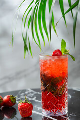 strawberry mojito with mint leaf on marble table. fresh drinks with strawberry and tropic branch on background