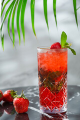 strawberry mojito with mint leaf on marble table. fresh drinks with strawberry and tropic branch on background