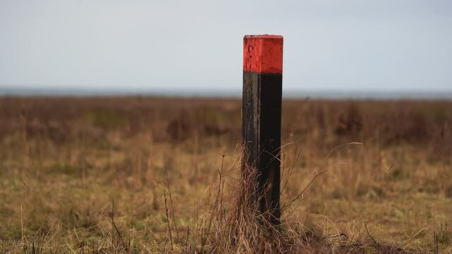 A wooden pole painted red in a natural reserve along the coast