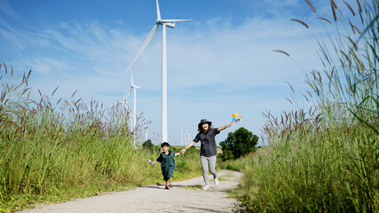 Mother and his son run around with windmills in a wind turbine field, mother teaching his son how to live in harmony with nature and technology, family relationships.