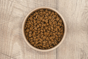 Dry pet food in ceramic bowl on wooden floor. Dog or cat pets food.