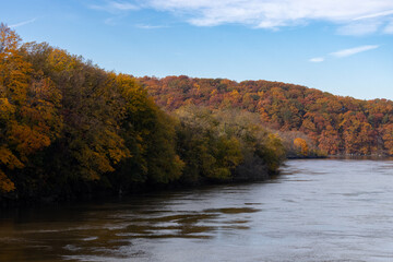 Autumn foliage on the Hudson River, near Spuyten Duyvil Creek, between the Bronx and Manhattan, beautiful Fall colors of orange leaves and a blue sky