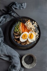 Miso ramen with mushrooms, carrots, zucchini and eggs on a dark background,top view,copy spase