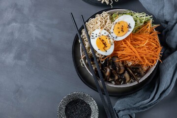 Miso ramen with mushrooms, carrots, zucchini and eggs on a dark background,top view,copy spase