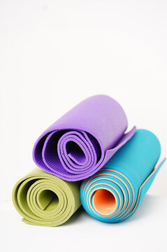 rolled up multicolored yoga mats on a white background. High quality photo