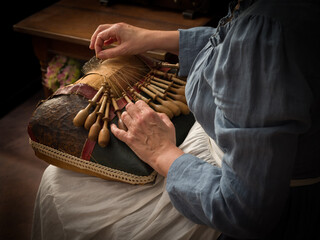 Woman at antique lace pillow with bobbins