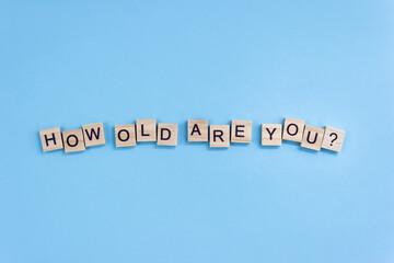 Interrogative sentence How old are you. Wooden blocks with letters on a blue background. Age...