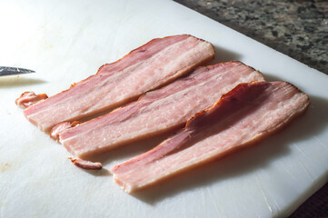 bacon sliced ​​on a white board with copy space to the left and selective focus